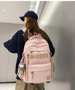 Detailed back view of a cute pink grid student backpack with letter embroidery and charm.
