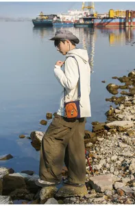 Vista de detalle de bolso de móvil para exterior, bandolera informal en naranja y azul marino.