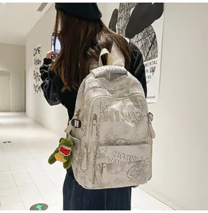 Detail view of grey nylon school backpack featuring custom letters and cute plush pendant.