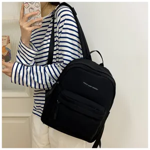 Detailansicht des minimalistischen schwarzen Canvas-Rucksacks mit Buchstaben, stylische Schultasche.