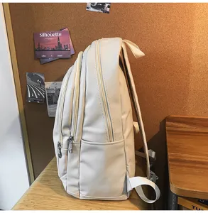 Gros plan profil d'un sac à dos minimaliste en cuir PU blanc cassé avec multiples poches.