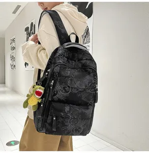 Stylish nylon backpack for women, large capacity school bag with letter print and cute dino pendant.