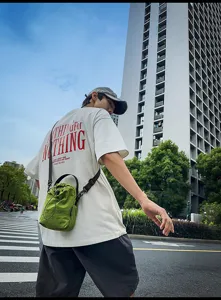 Detail view of casual minimalist green drawstring bucket bag worn by model on street backdrop.