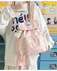Detailansicht des niedlichen pinken Sternen-Schulrucksacks mit Vordertasche und Anhänger.