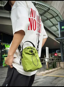 Green drawstring bucket bag detail showing adjustable strap and stylish design.