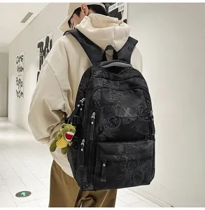 Stylish black nylon large capacity school backpack with letters and cute dinosaur pendant.