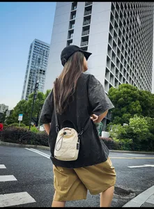 Casual drawstring bucket bag detail shot in urban street scene, simple minimalist style fashion.