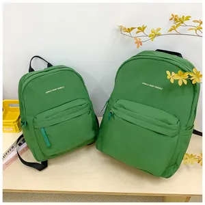 Grüner Canvas Schulrucksack Detail mit Vordertasche mit Reißverschluss und stilvollem Buchstaben-Druck.