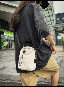 Detailed view of casual minimalist women drawstring bucket bag with shoulder strap and handle.