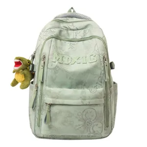 Green nylon school backpack detail with doodle print, letter embroidery and cute dinosaur plush.
