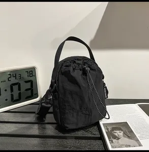 Minimalist casual drawstring women's bucket bag in black nylon with top handle and strap.