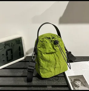 Green drawstring bucket bag detail, casual nylon crossbody bag featuring black handle and strap.