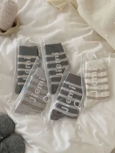 Detail shot of cozy striped wool socks in transparent packaging bags on soft white bedding.