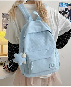 Detailed view of light blue student backpack with grid texture, front pocket and star charm.