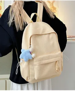 Close-up detail of beige corduroy backpack with soft texture and cute star pendant.