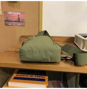 Detailansicht der grünen Nylon Umhängetasche auf Holztisch, lässige Streetwear Sling Bag.