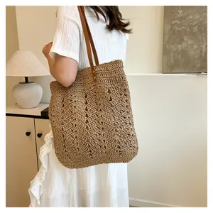 Borsa shopper in paglia intrecciata da donna, grande borsa a spalla con manici marroni, spiaggia.