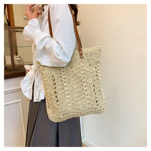 Vista dettagliata della borsa tote in paglia intrecciata indossata a spalla con texture vintage.