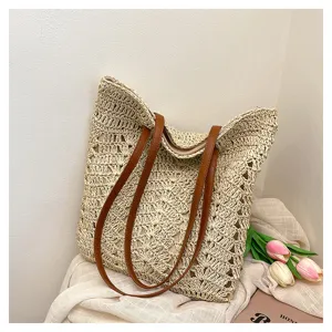 Dettagli della borsa tote in paglia intrecciata con manici in pelle marrone, ideale per la spiaggia.