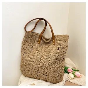 Vista dettagliata della borsa tote in paglia intrecciata con motivo traforato e manici in pelle.