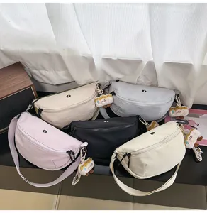 Close-up detail view of casual multi-color chest sling bags displayed together on dark shelf.