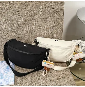 Detail view of Japanese casual nylon crescent chest bag with cute plush pendant and zipper.
