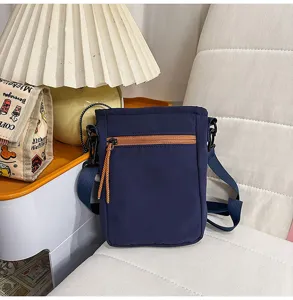 Detalle del bolso cruzado azul para exteriores con cremallera naranja y diseño de estilo diario casual.