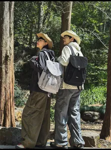 Scène de détail de sac à dos de voyage avec deux modèles stylés en forêt naturelle.