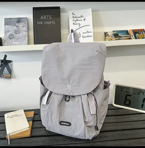 Détail de sac à dos de voyage gris montrant la texture du tissu et les détails de marque.