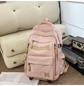 Pink student backpack detail view, featuring grid fabric, front pockets, and letter decorations.