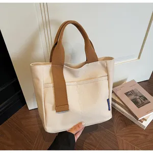 Dettaglio in primo piano della borsa in tela beige con manici marroni in una scena quotidiana.