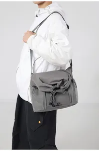 Detailed shot of grey streetwear crossbody messenger bag with mesh side pockets and drawstring.