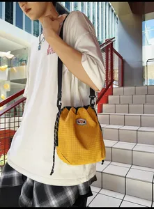 Detail view of the casual nylon drawstring bucket bag in yellow plaid, showing strap and texture.
