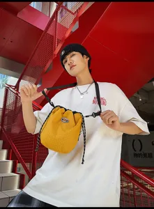 Detailed view of the yellow grid nylon drawstring bucket bag worn casually by a model.