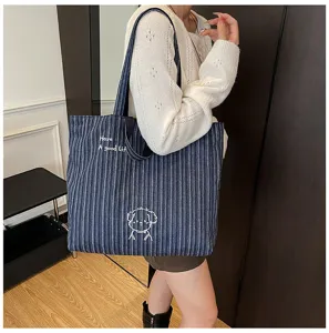 Vista dettagliata di una grande borsa tote a righe in tela con ricamo carino e tracolla robusta.