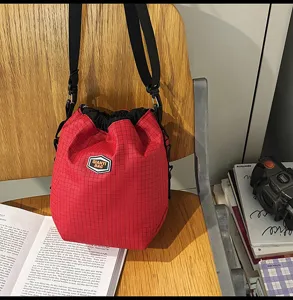 Detail view of the stylish red plaid nylon drawstring bucket bag with black shoulder strap.