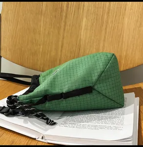Green nylon grid drawstring bucket bag detail, casual lightweight unisex travel crossbody.
