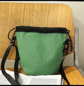 Green grid nylon drawstring bucket bag, casual lightweight shoulder crossbody bag for daily travel.