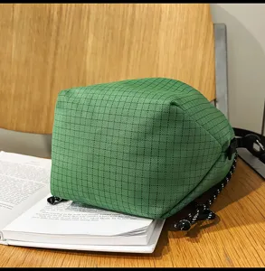 Green checkered nylon fabric drawstring bucket bag detail, casual lightweight style.