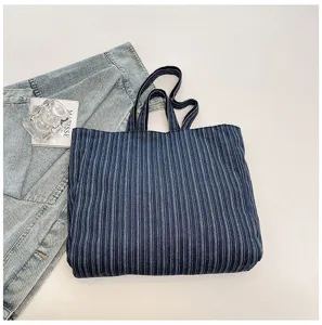 Primo piano della borsa tote in denim a righe, evidenziando la trama del tessuto e i manici.