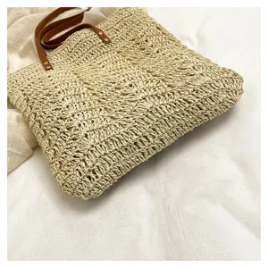 Vista dettagliata della borsa tote in paglia beige con trama, stile spiaggia fatto a mano.