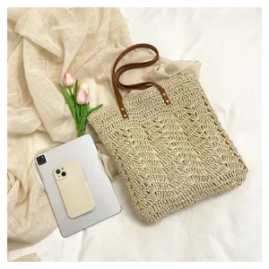 Vista dettagliata della borsa tote in paglia intrecciata con motivo traforato e manici in pelle.