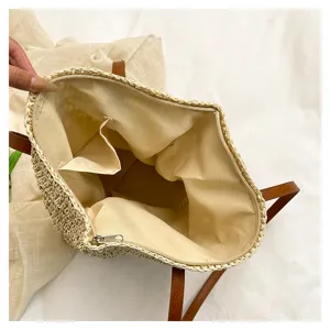 Vista interna dettagliata di una borsa tote in paglia con chiusura zip e tasca interna.