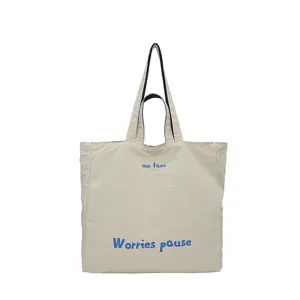 Vista dettagliata della borsa tote casual beige in tela con doppi manici e stampa blu brillante.