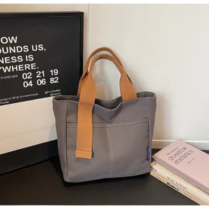 Dettaglio borsa shopper in tela casual, elegante borsa da donna con manici marroni e tasca.