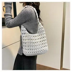 Vista dettagliata della borsa a spalla bianca in maglia traforata indossata dalla modella.