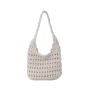 Dettaglio della trama a maglia beige della borsa a tracolla casual con motivo traforato.