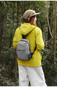 Vista detallada de la mochila casual gris a cuadros de nylon en un bosque exterior.
