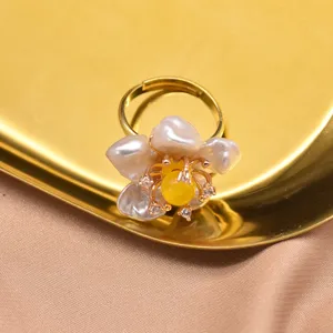 Primo piano dettagliato dell'elegante anello con fiore di perla barocca e finitura dorata.