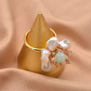 Dettaglio squisito di anello con fiore di perla barocca, splendidi cristalli verdi.